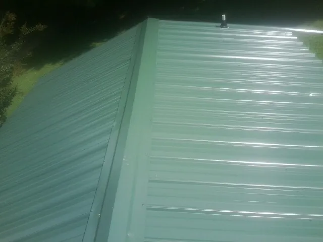New green metal panels meeting at the ridge of a roof — Flat Roof Repair work by our crew in Poughkeepsie