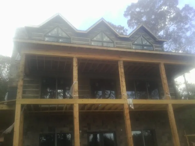 Dormers and porch framing on a large log home under construction — Roof Coating work by our crew in Poughkeepsie