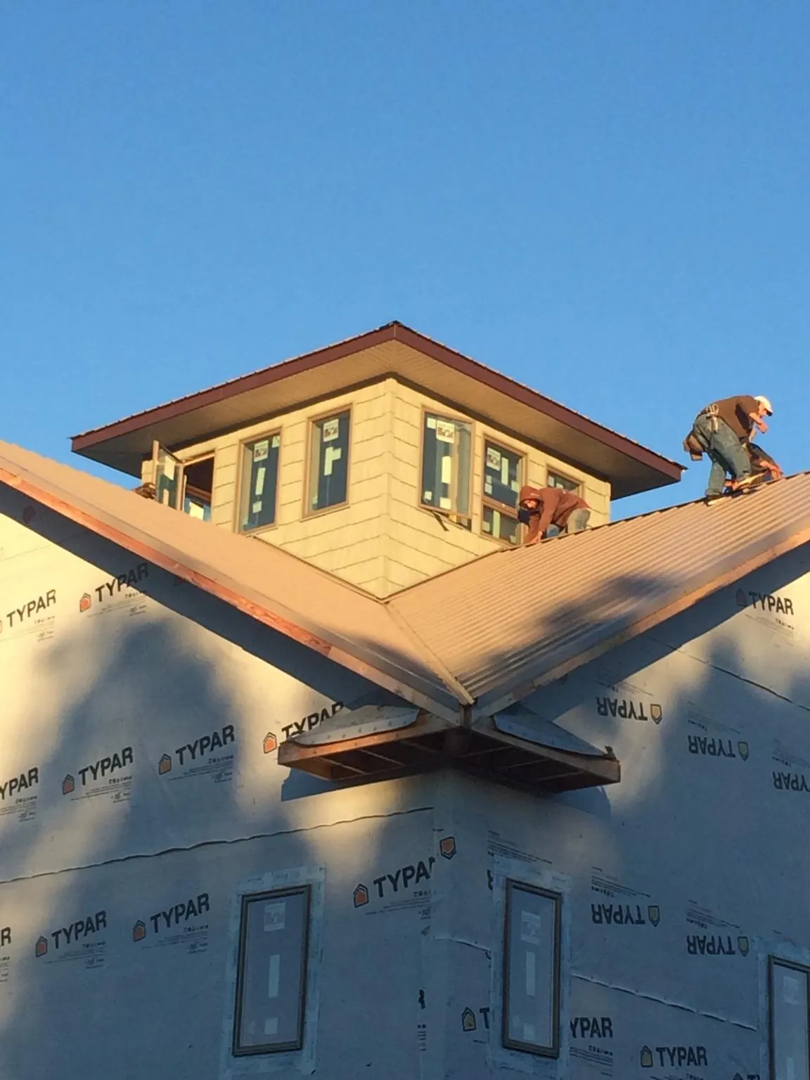 Roofers working around a rooftop cupola on a new metal roof at sunset — Roof Waterproofing in Poughkeepsie by Roofing Brothers